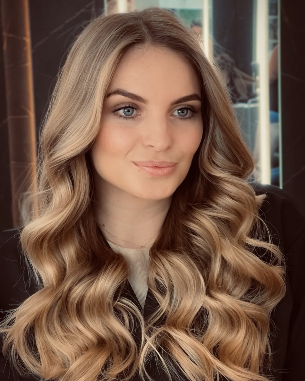 Portrait of Joice with long, wavy blonde hair, smiling softly
