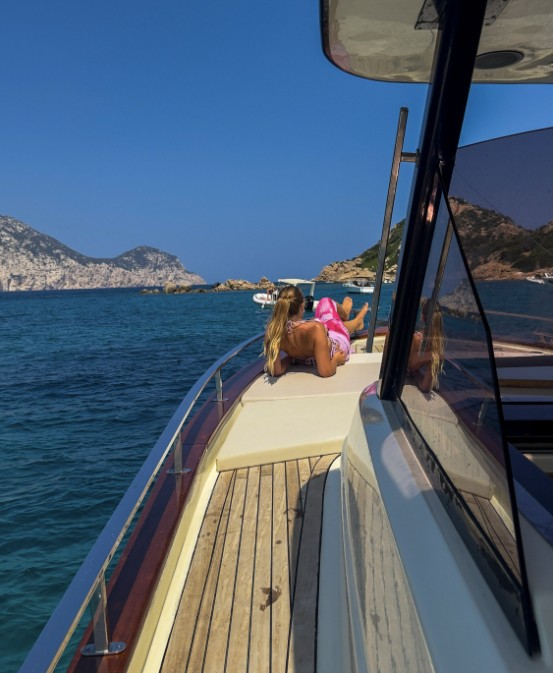 View from the bow of a boat, with blue sea and the coast behind