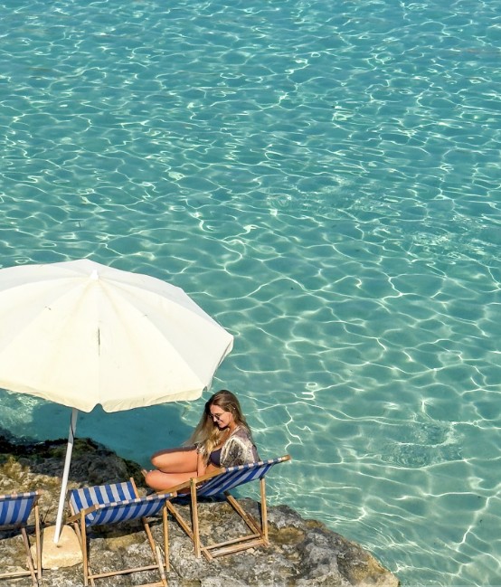 Turquoise sea with a white parasol and deckchairs on the rocks